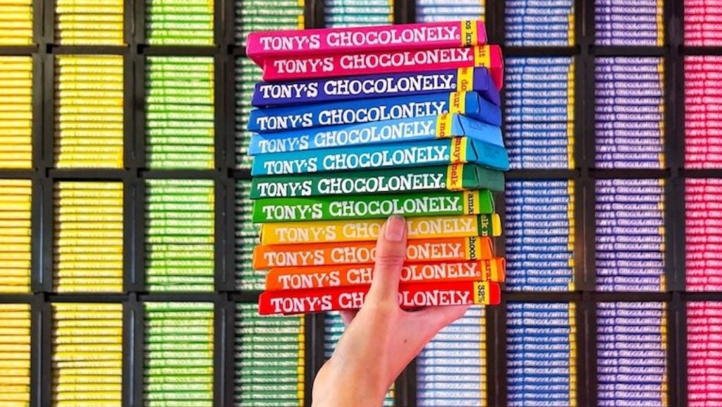 multicoloured chocoloate bars held in women's hand against background of multicoloured chocolate bars